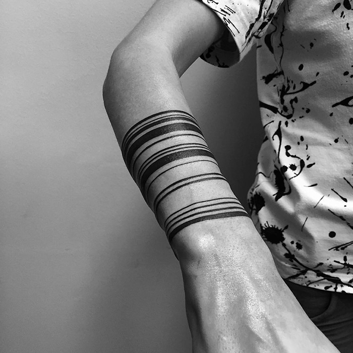 Minimalist digitally-designed tattoo featuring black concentric line bands on a person's forearm.