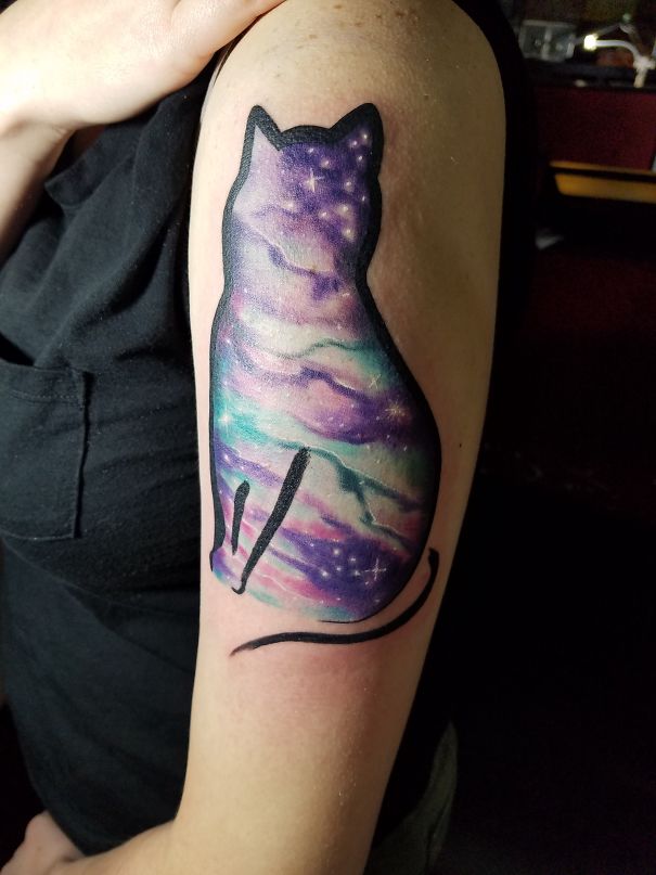 Tattoo of a cat silhouette with a galaxy design on an arm, showcasing a creative cat tattoo idea.