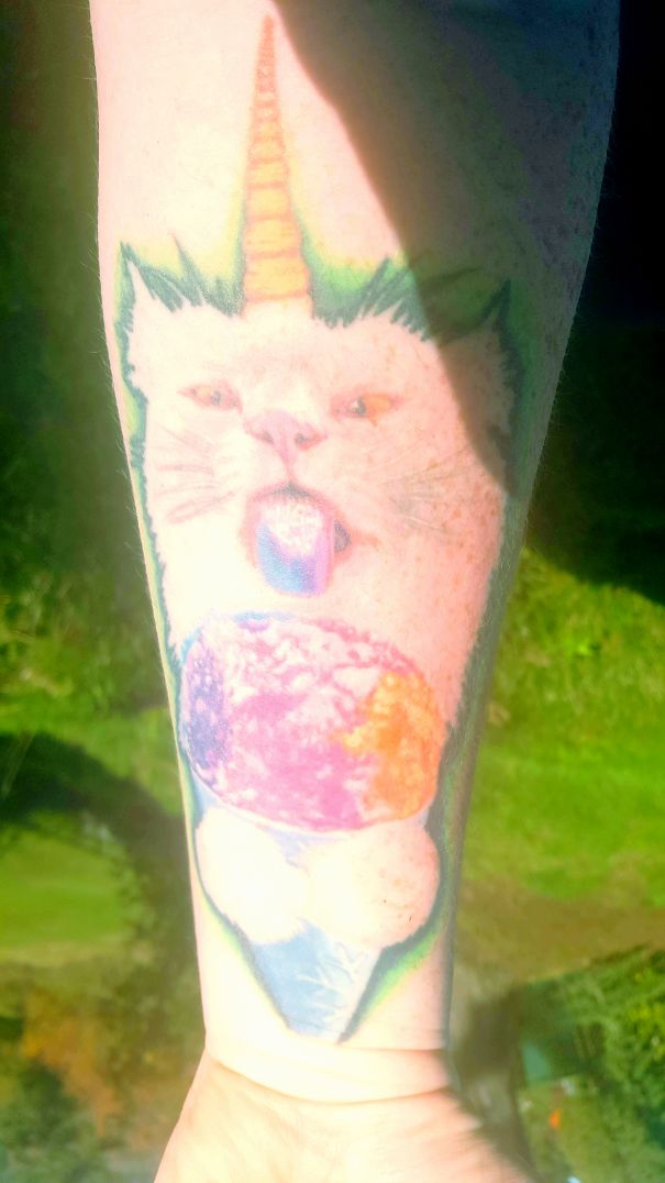 Colorful cat tattoo with a unicorn horn and ice cream design on a forearm, ideal for cat person expression.
