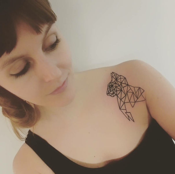 Woman with geometric cat tattoo on shoulder, expressing her love for cats.