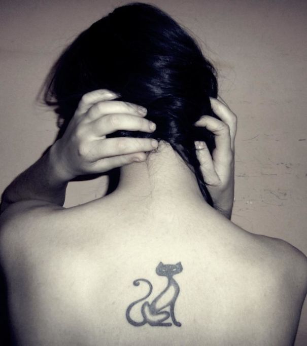 Minimal cat tattoo on upper back, showcasing a simple and stylish cat design for cat lovers.