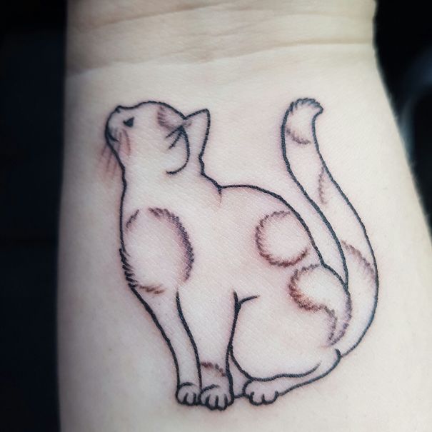 Minimalistic outline of a cat tattoo on inner wrist, showcasing a simple yet elegant cat design.