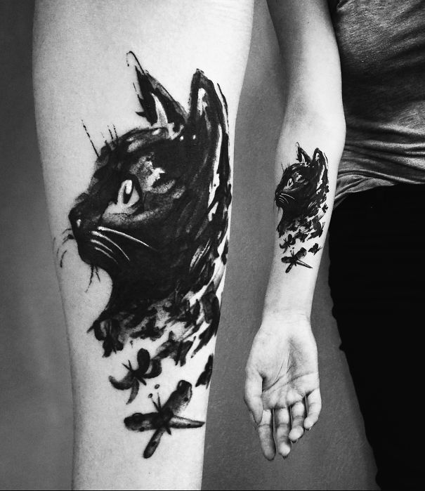 Black cat tattoo design on forearm, depicting artistic brush strokes and dragonflies.