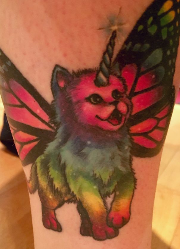 Colorful cat tattoo with butterfly wings and a unicorn horn.