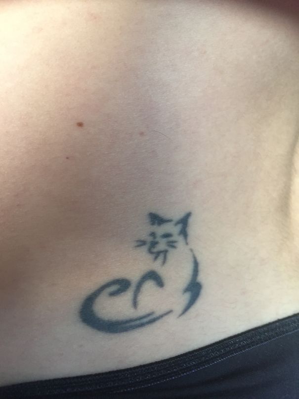 Simple cat tattoo design on lower back, showcasing minimalistic black ink art for cat person enthusiasts.