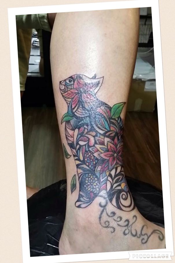 Colorful cat tattoo design on the leg, featuring intricate patterns and floral elements.