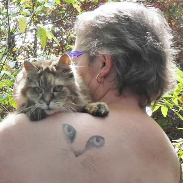 Person holding a cat with a cat tattoo on their shoulder, showing off cat tattoo ideas for enthusiasts.