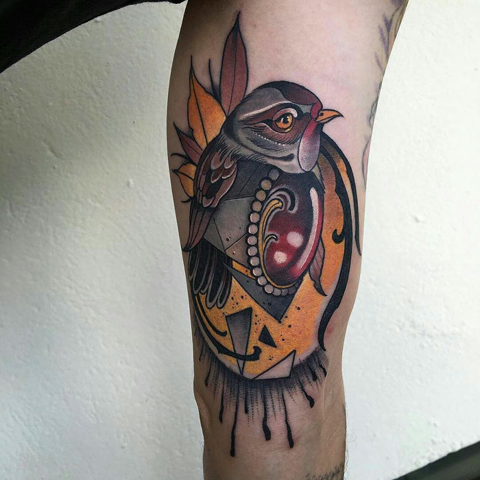 Colorful small bird tattoo with geometric designs on a person's leg, showcasing unique artistic style.