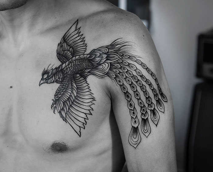 Intricate small bird tattoo on shoulder, showcasing detailed feathers and artistic design.