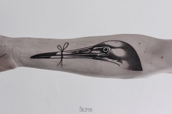 Unique small bird tattoo featuring a detailed design on a forearm.