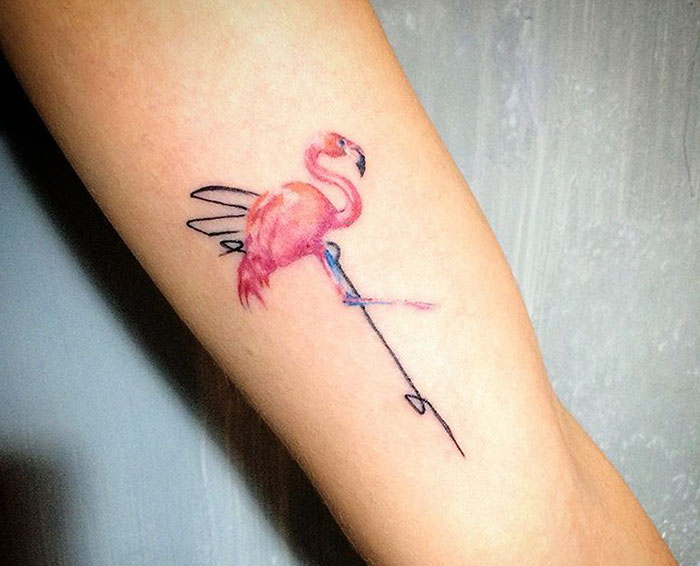 Colorful small bird tattoo of a flamingo on a person's forearm, showcasing unique small bird tattoo design.