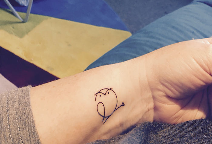 Minimalist small bird tattoo on a wrist, featuring simple line art design.