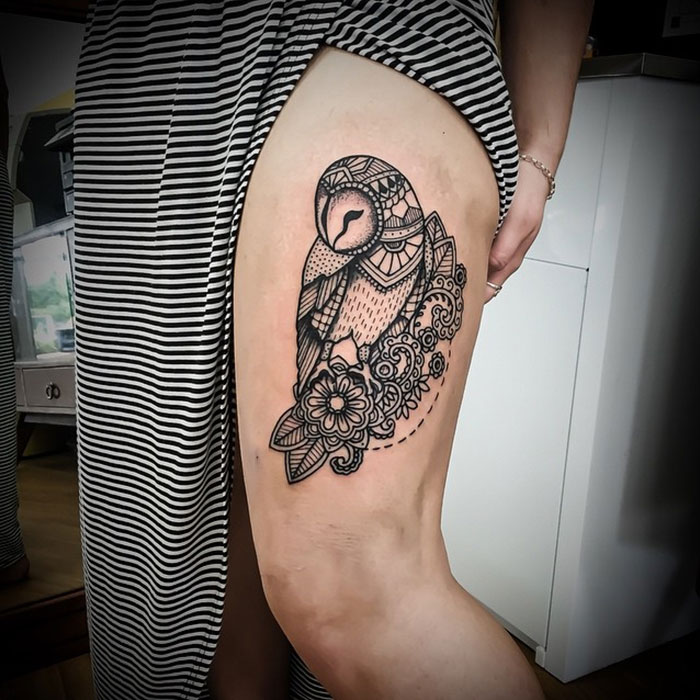Unique small bird tattoo with floral design on a person's thigh.