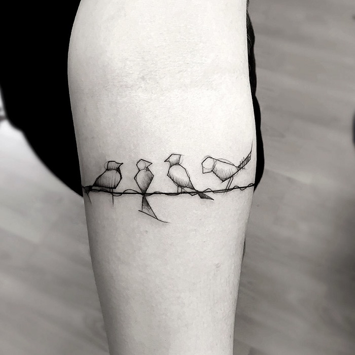 Minimalist line art of small birds perched in a tattoo design on an arm, showcasing unique small bird tattoos.