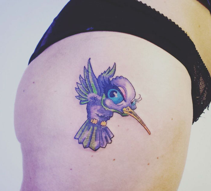 Colorful small bird tattoo on skin, showcasing vibrant and unique design elements.