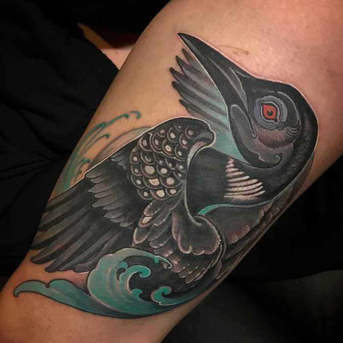Intricate small bird tattoo featuring detailed wings and vibrant colors.