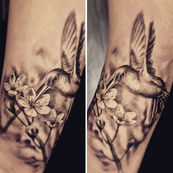 Detailed small bird tattoo featuring a hummingbird with flowers on arm.