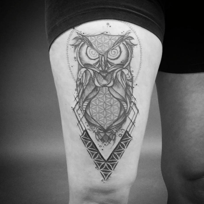 Geometric small bird tattoo design on a person's thigh, featuring intricate owl patterns.