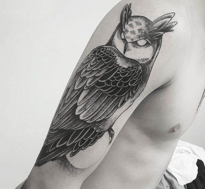 Unique small bird tattoo of an owl on a person's arm, showcasing intricate detail and shading.