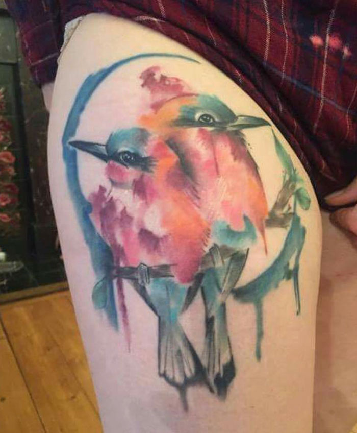 Watercolor small bird tattoos featuring two vibrant birds on skin, perfect for unique tattoo inspiration.