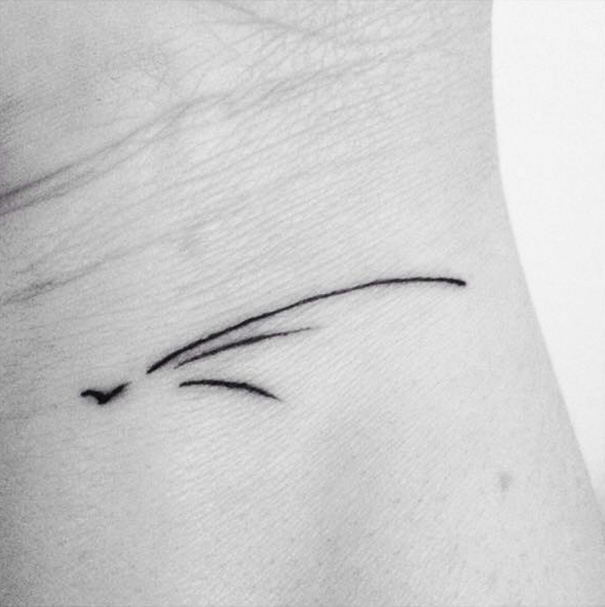 Minimalist cat tattoo design on wrist, showcasing a simple and elegant expression of being a cat person.