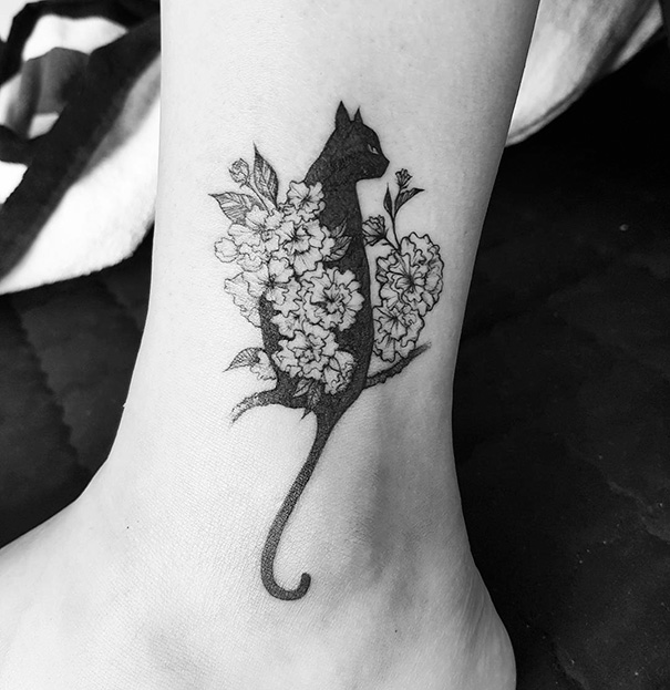 Cat tattoo design on ankle with floral accents, showcasing cat person style.