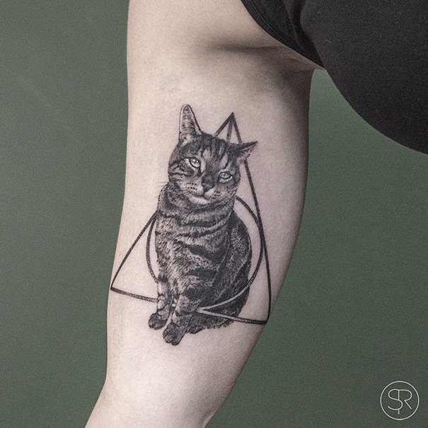 Cat tattoo with geometric shapes on a person's forearm, showcasing a detailed feline design.