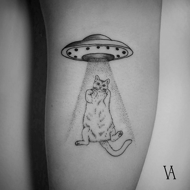 Cat tattoo depicting a UFO beaming up a cat on a person's arm.