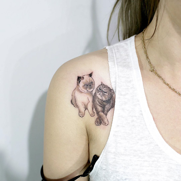 Cat tattoo featuring two cats on a person's shoulder, showcasing a minimalist and artistic design.