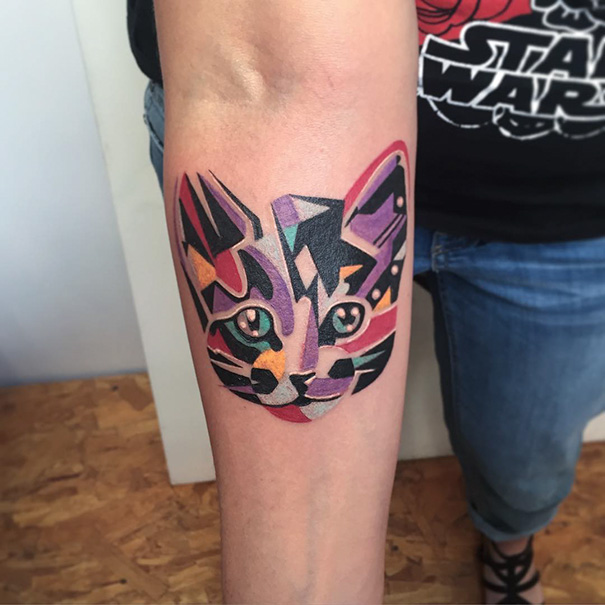 Colorful geometric cat tattoo on forearm, showcasing vibrant expression for cat lovers.