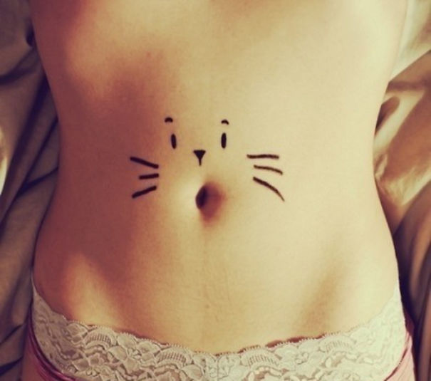 Cat tattoo on a person's stomach, designed as a simple outline with whiskers and a nose.