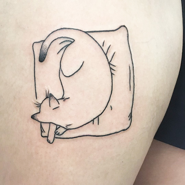 Minimalist cat tattoo of a curled-up cat on a cushion, symbolizing a cat person's affection.