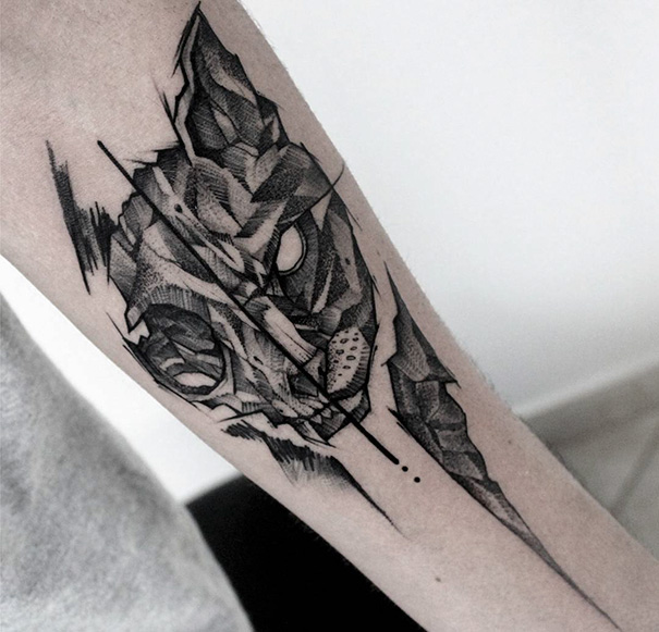Geometric cat tattoo on forearm, showcasing intricate black ink design.