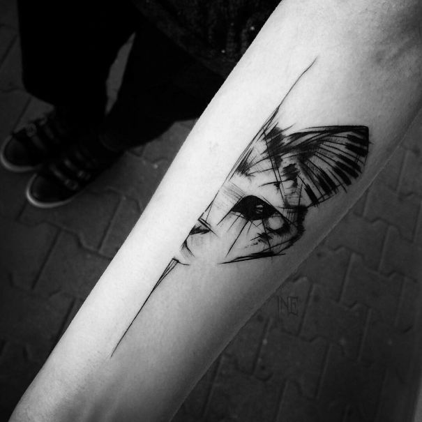 Abstract cat tattoo design on forearm, featuring sharp lines and shading.