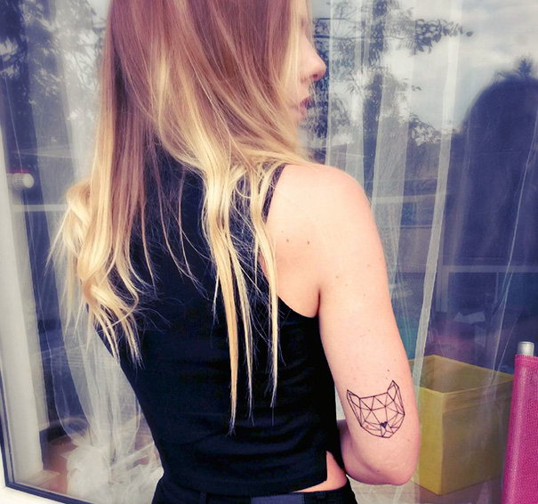 Woman with geometric cat tattoo on her arm, showcasing cat tattoo ideas for self-expression.