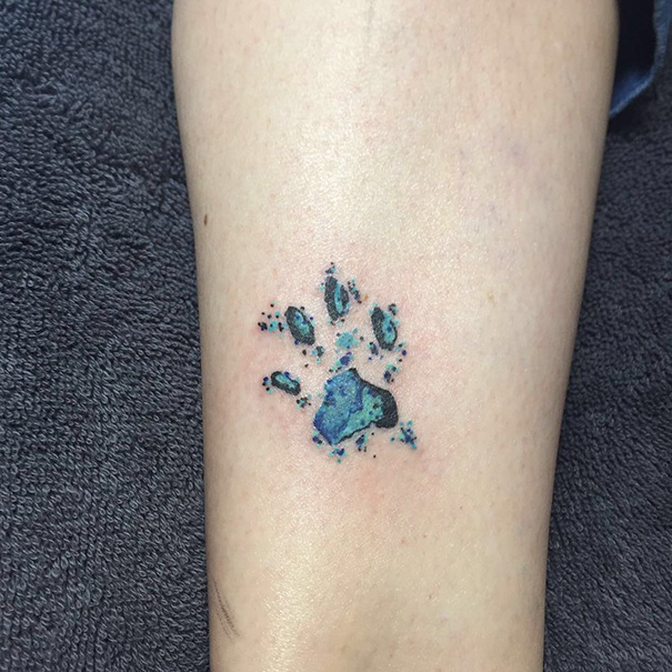 Colorful cat paw tattoo on forearm, showcasing unique cat tattoo design.