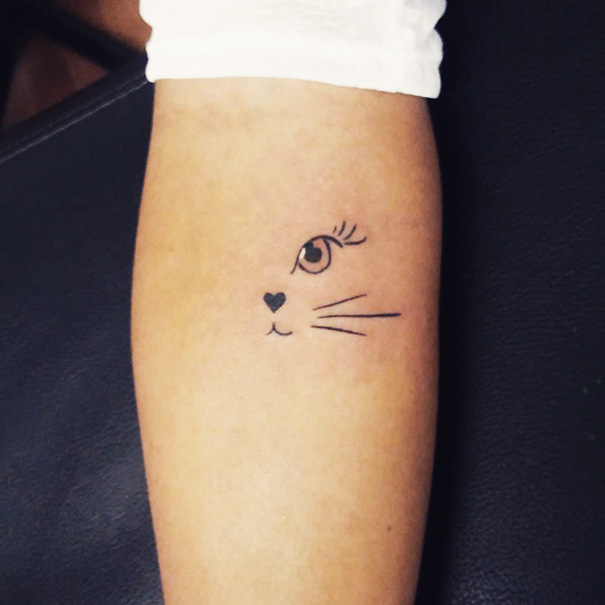 Cat tattoo design on forearm with minimalistic lines depicting a cat's eye, nose, and whiskers.