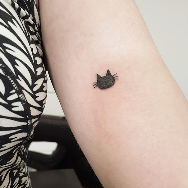 Minimalist cat tattoo on forearm, perfect for cat person self-expression.