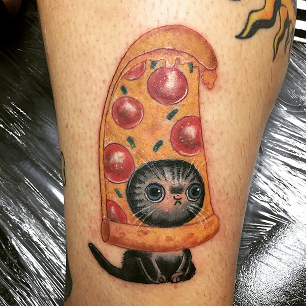 Cat tattoo featuring a cute black cat peeking out of a pepperoni pizza slice.