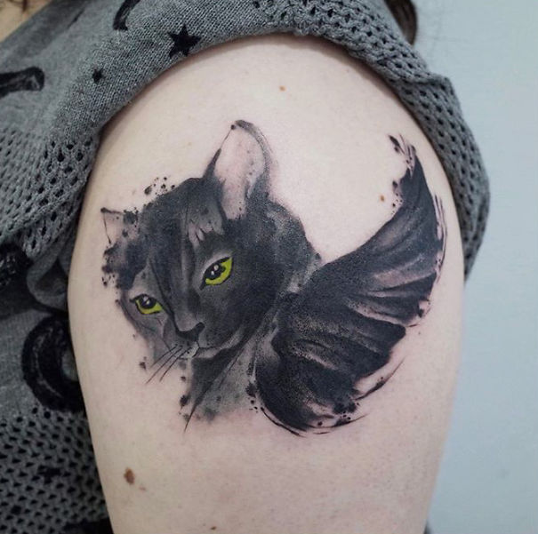 Cat tattoo on arm featuring a detailed, artistic design with wings, showcasing self-expression as a cat person.