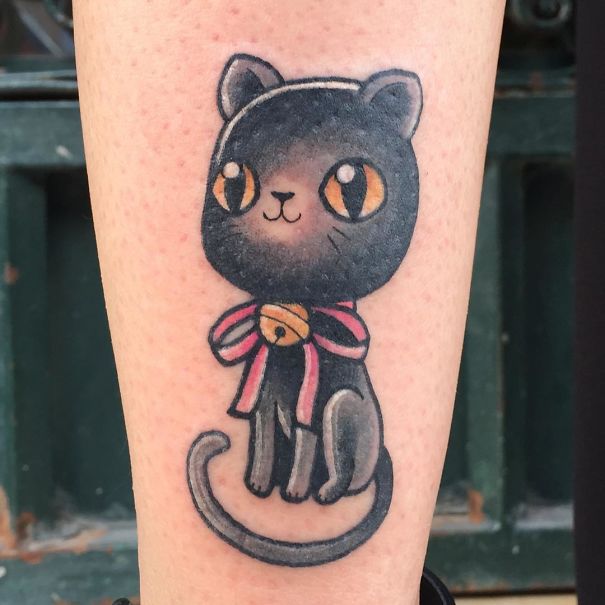 Cute black cat tattoo with a bell and bow, capturing a playful expression for cat tattoo enthusiasts.