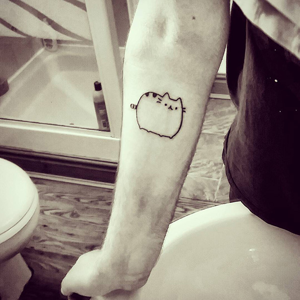 Minimalist cat tattoo on a person's forearm, showcasing cat person expression in a bathroom setting.