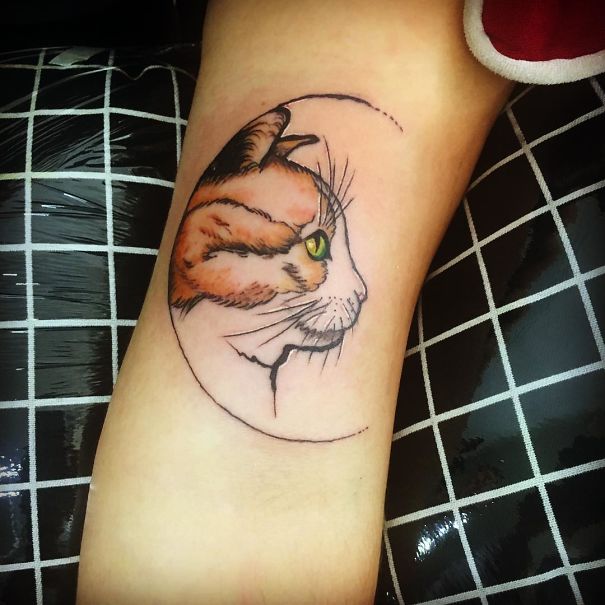 Cat tattoo on arm, featuring a detailed cat profile with a circular design.