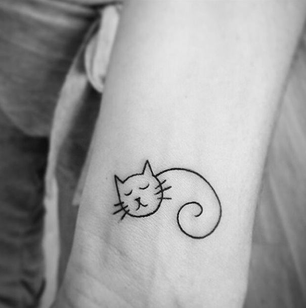 Minimalist cat tattoo on forearm, showcasing unique expression for cat lovers.