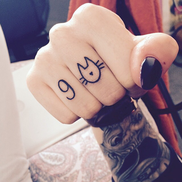 Cat tattoo on finger showcasing minimalist cat face design with number 9.