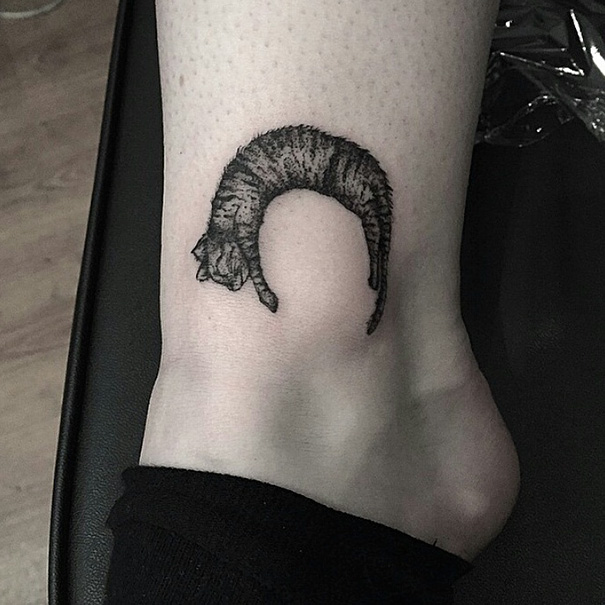 Cat tattoo on ankle depicting a curled-up feline design.