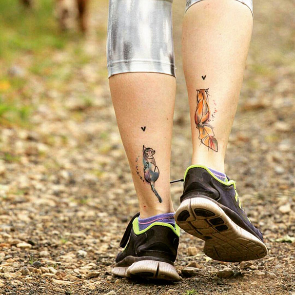 Two colorful cat tattoos on a person's calves, showcasing unique cat tattoo ideas.
