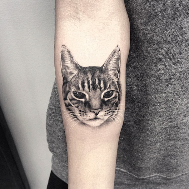 Realistic cat tattoo on forearm showcasing detailed fur and expressive eyes, ideal for cat tattoo enthusiasts.