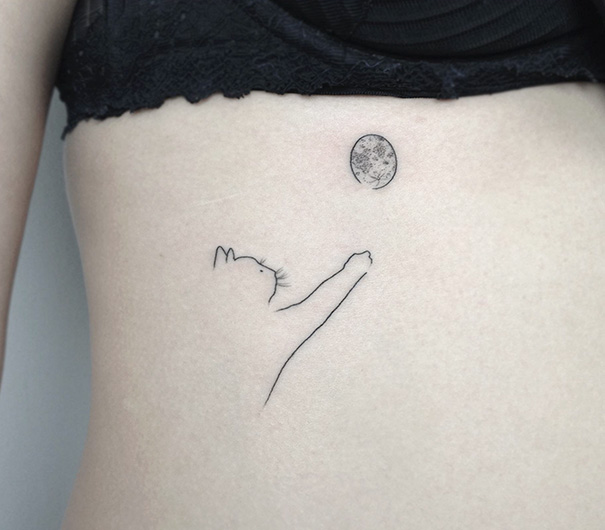 Minimalist cat tattoo reaching for a moon on someone's side, expressing cat person identity.