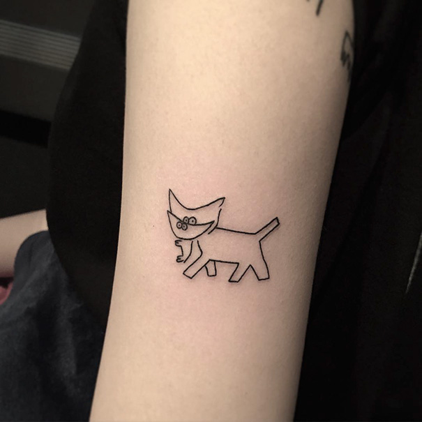 Minimalist cat tattoo on the arm, showcasing unique cat art for enthusiasts.